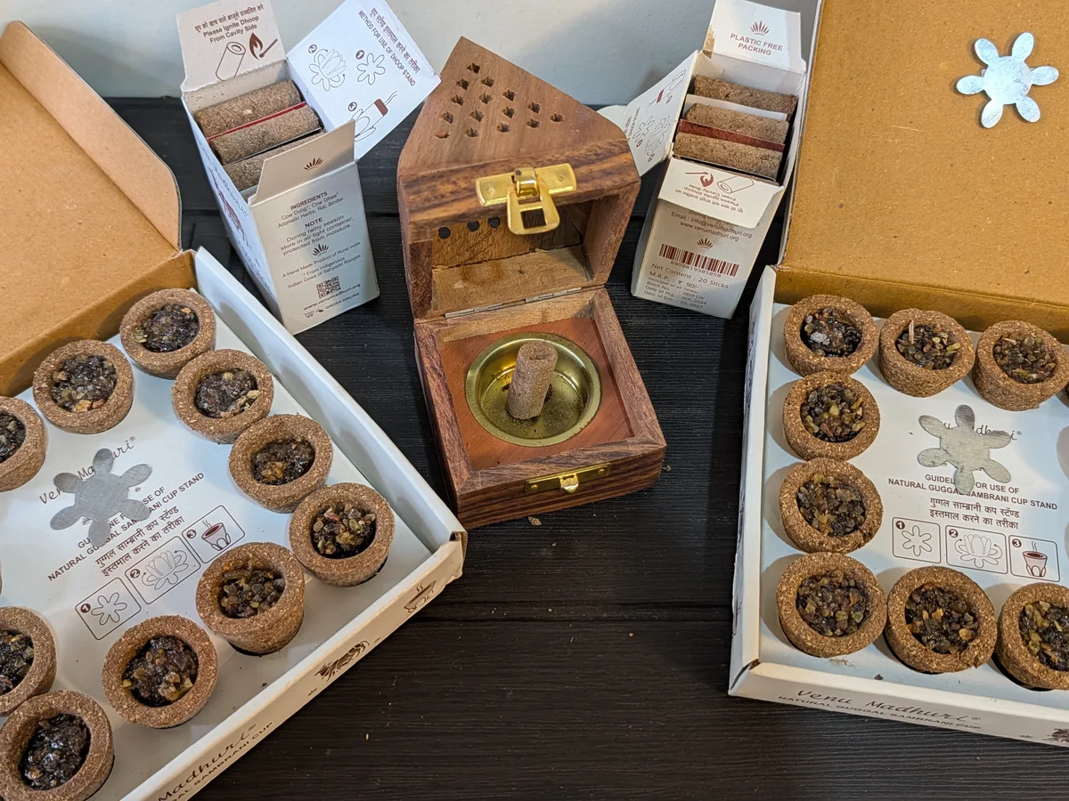 Two gift boxes open, showing trays of guggal sambrani cups, packs of dhoop sticks and the wooden pyramid holder