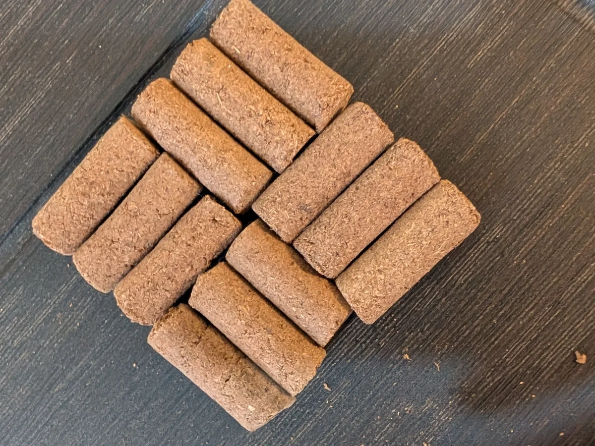 Twelve cow dung and ghee dhoop sticks stacked on a dark table